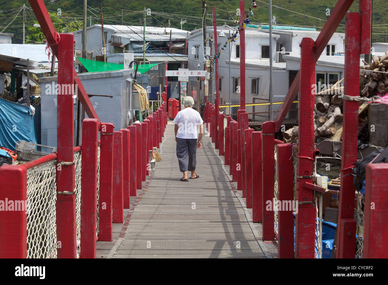 Alte Frau kreuzt Fußgängerbrücke in Fischerdorf Tai O. Lantau Island, Hongkong Stockfoto