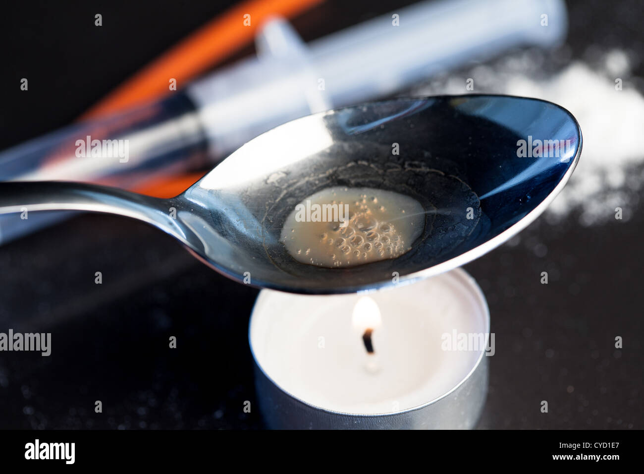 Heroin wird in einem Löffel über einer Kerze gekocht Stockfoto