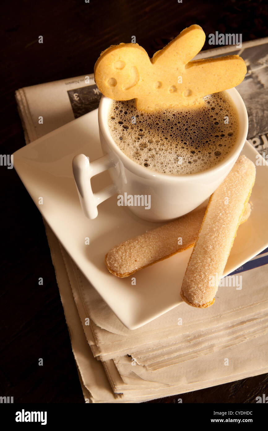 Lebkuchen-Männer-Cookie mit heißem Kaffee auf gefalteten Zeitungen Stockfoto
