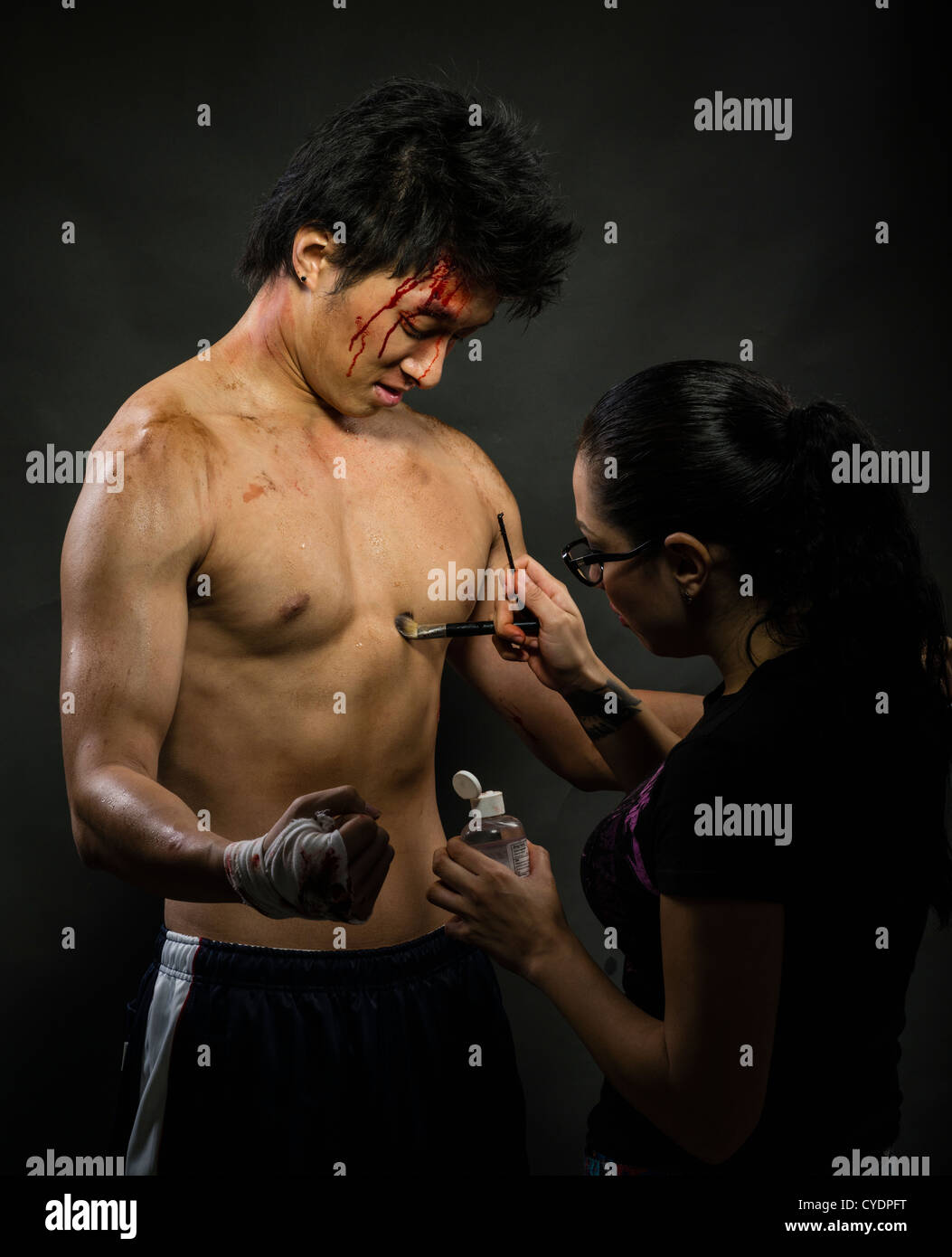 Make-up / Special Effects Künstler gilt Schmutz und Blut an den Körper eines Modells / Schauspieler Stockfoto