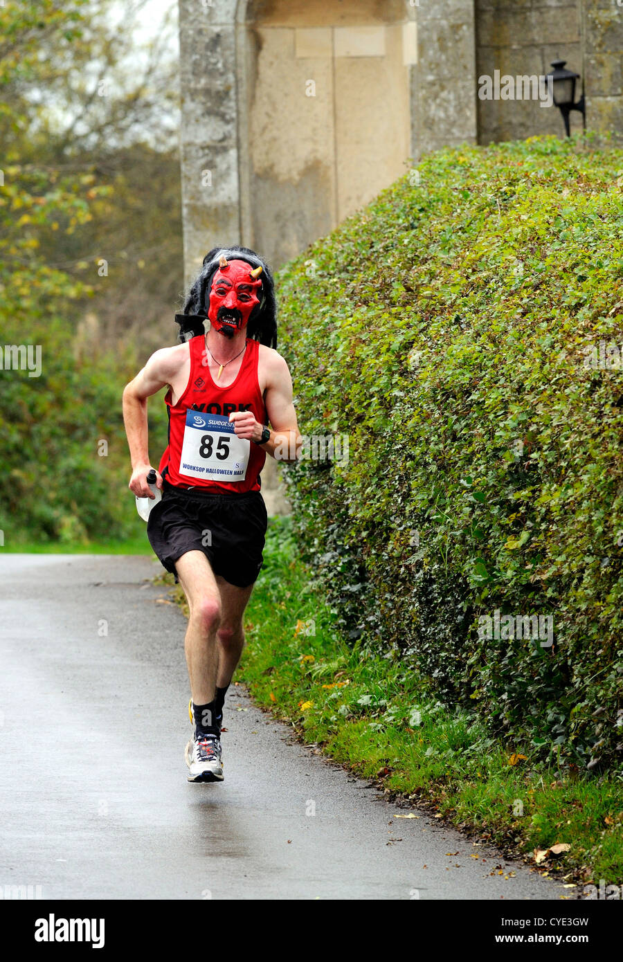 Männlichen Marathonläufer mit einer roten Teufel Maske während der Worksop Halloween Halbmarathon durch den Clumber Park, Nottinghamshire. Stockfoto