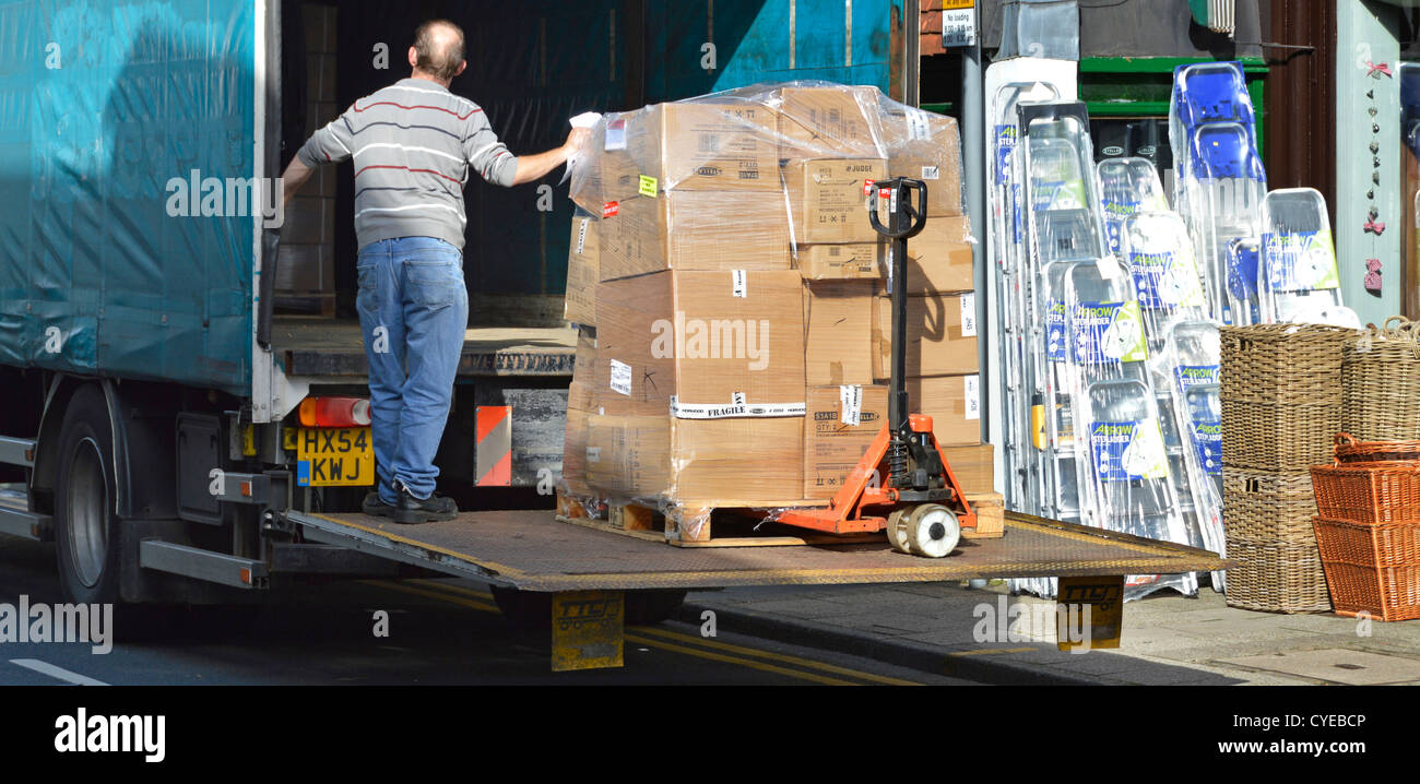 High Street Shop erhält der Lieferant ware Lieferung von Kartons auf Palette Trolley auf Heckklappe durch LKW-Fahrer Sevenoaks UK abgesenkt werden gestapelt Stockfoto