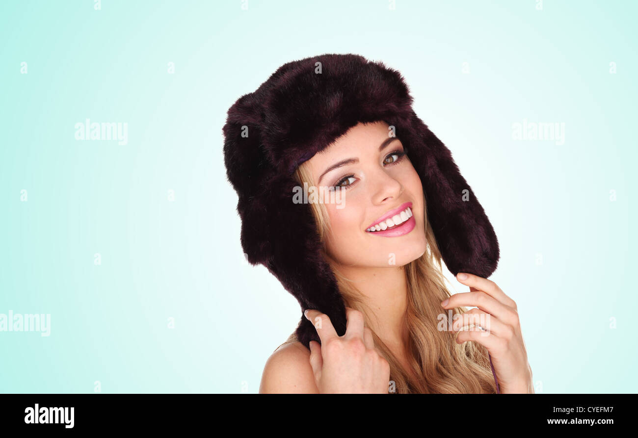 Attraktive junge Frau trägt eine Winter-Pelzmütze mit Ohrenklappen geben ein schönes Lächeln Stockfoto
