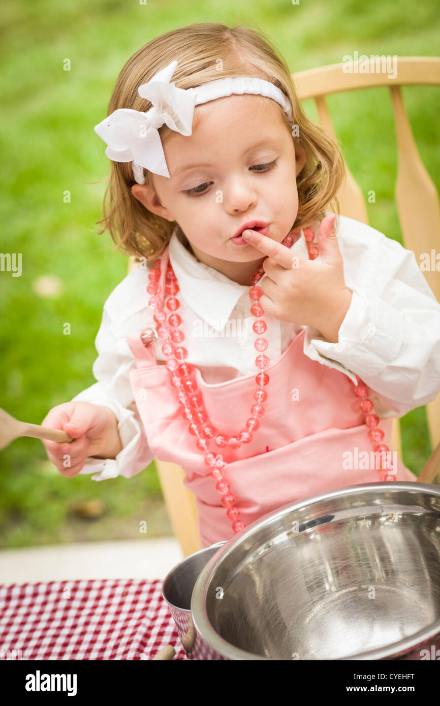 Glücklich entzückende kleine Mädchen spielen Koch in ihrem rosa Outfit. Stockfoto