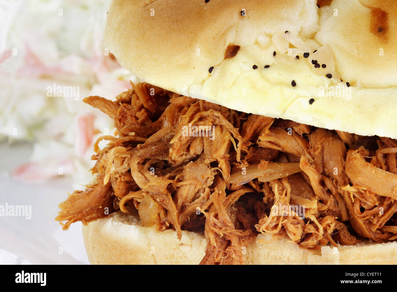 Nahaufnahme des gezogenen Hähnchen-Sandwich mit Krautsalat im Hintergrund. Stockfoto