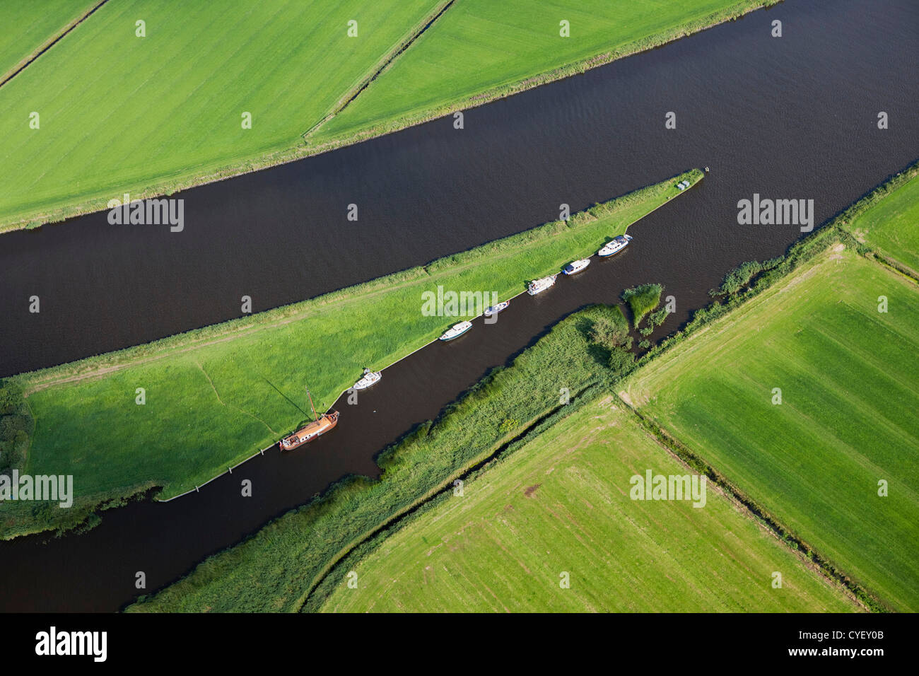 Die Niederlande, in der Nähe von Uitwellingerga-Antenne. Ackerland und Boote verankert auf der kleinen Insel. Stockfoto