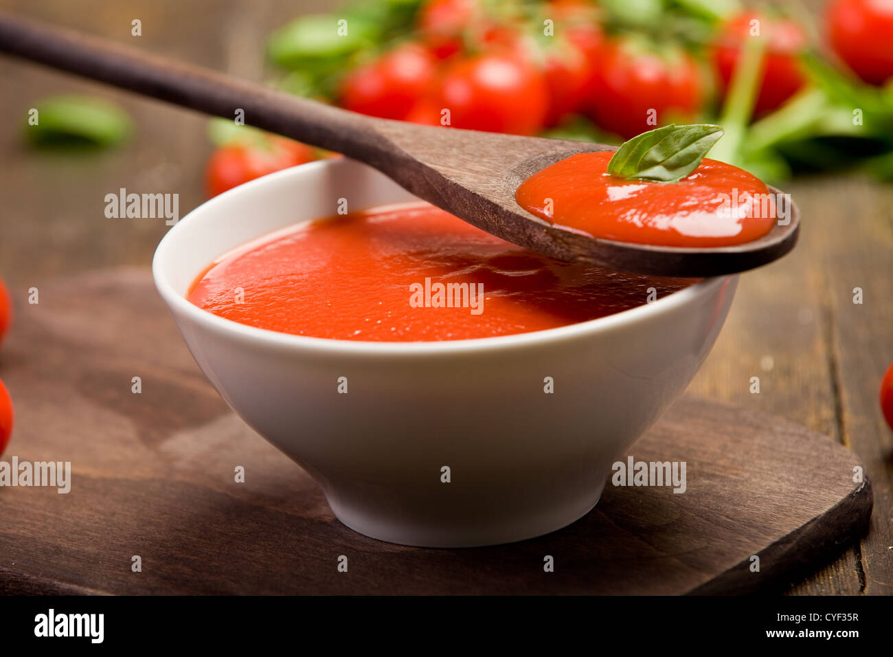 frische rote Tomatensauce mit Basilikum und Holzlöffel Stockfoto