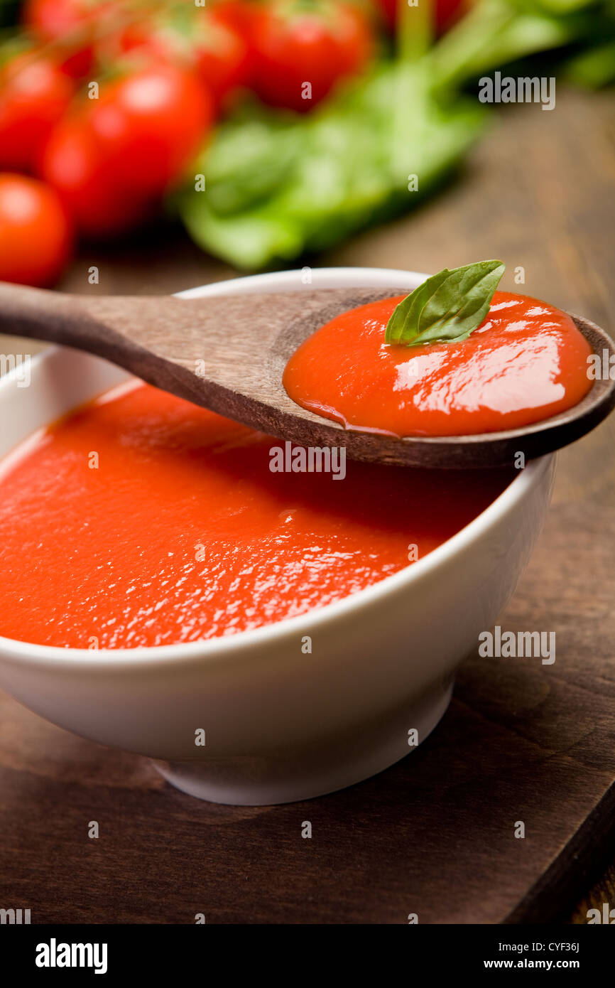 frische rote Tomatensauce mit Basilikum und Holzlöffel Stockfoto