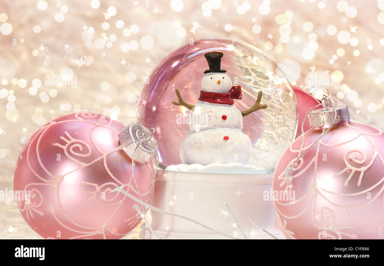 Schneekugel mit rosa Verzierungen mit Glanz-Hintergrund Stockfoto