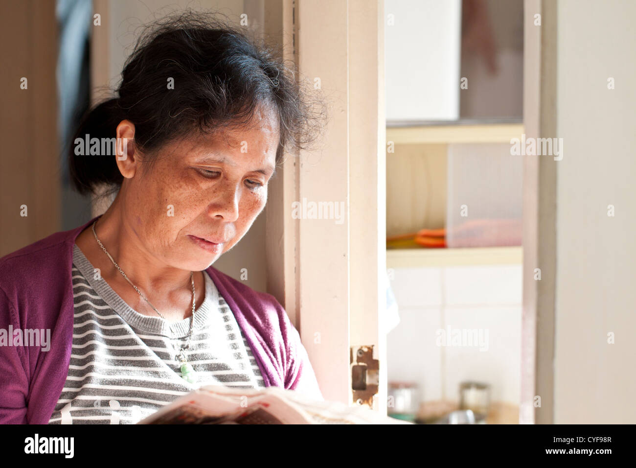 Ein 50er Jahre asiatische Frau liest Zeitung zu Hause Stockfoto