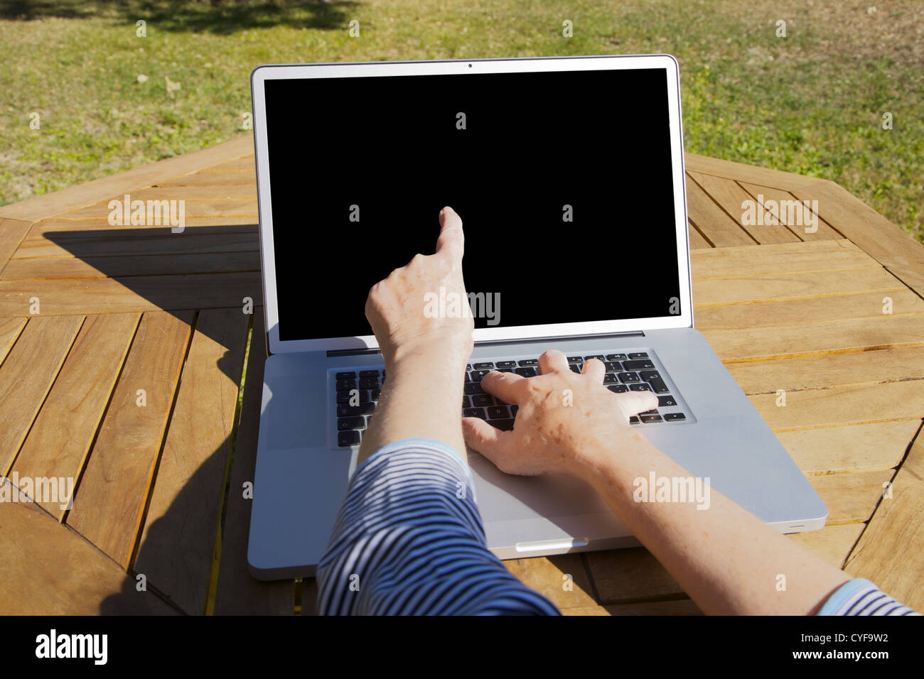 Hände der alten Frau, die auf tragbaren Computer tippen Stockfoto