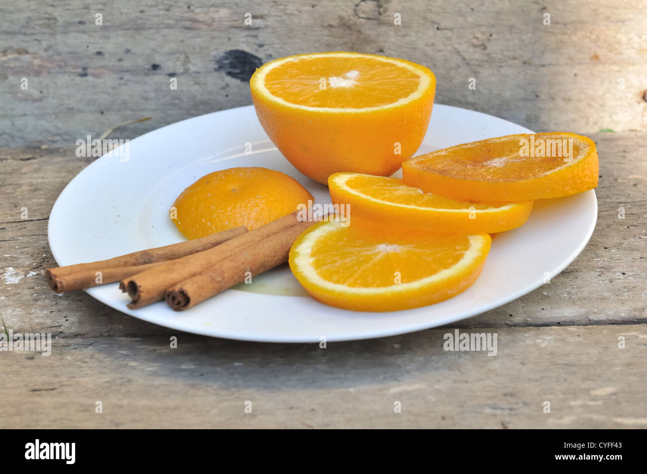 Orangenscheibe und Stangen Zimt auf einem Teller auf hölzernen Hintergrund Stockfoto