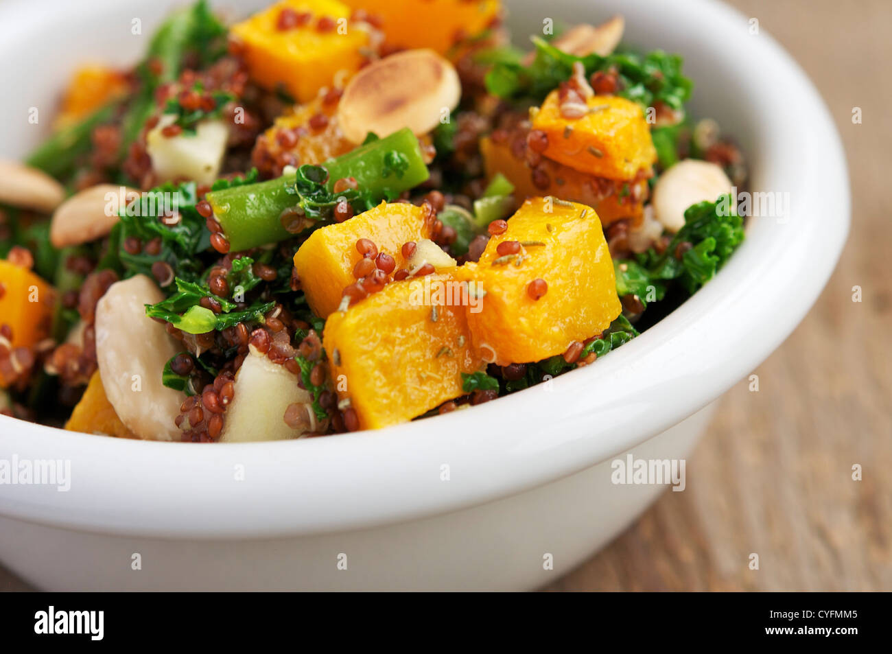 Ein warmer Salat mit rote Quinoa, grüne Bohnen, Kürbis, Grünkohl, Apfel und Mandeln. Stockfoto