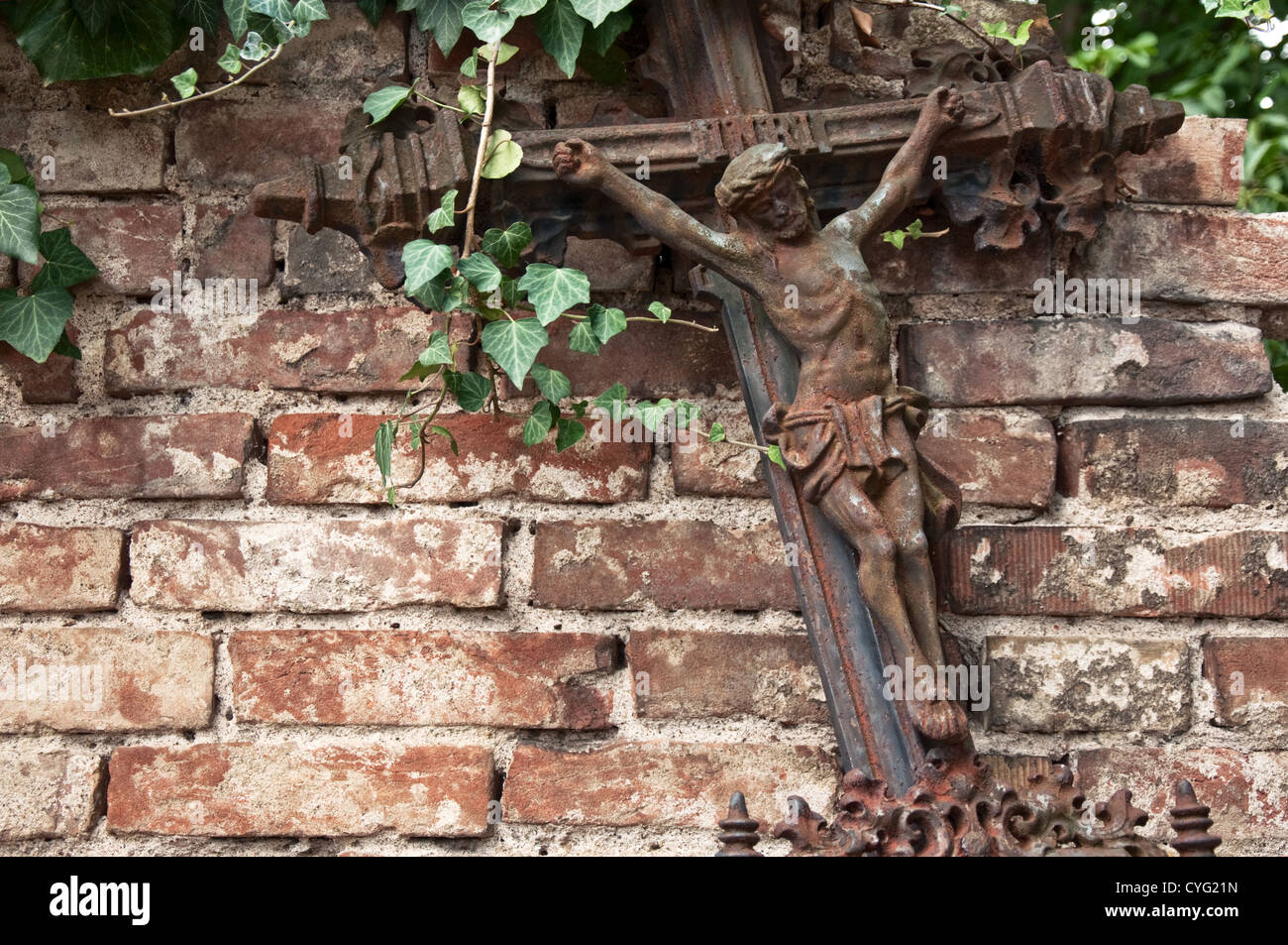 Alte rostige Kreuzigung stützte sich auf die Brickwall einen Friedhof. Stockfoto
