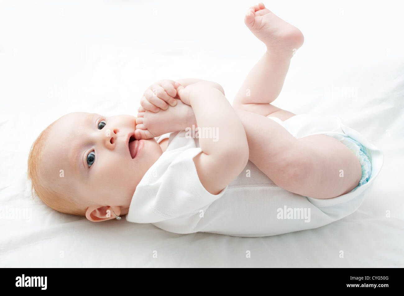 Cute Baby Girl saugen ihre Zehen auf weißem Hintergrund Stockfoto