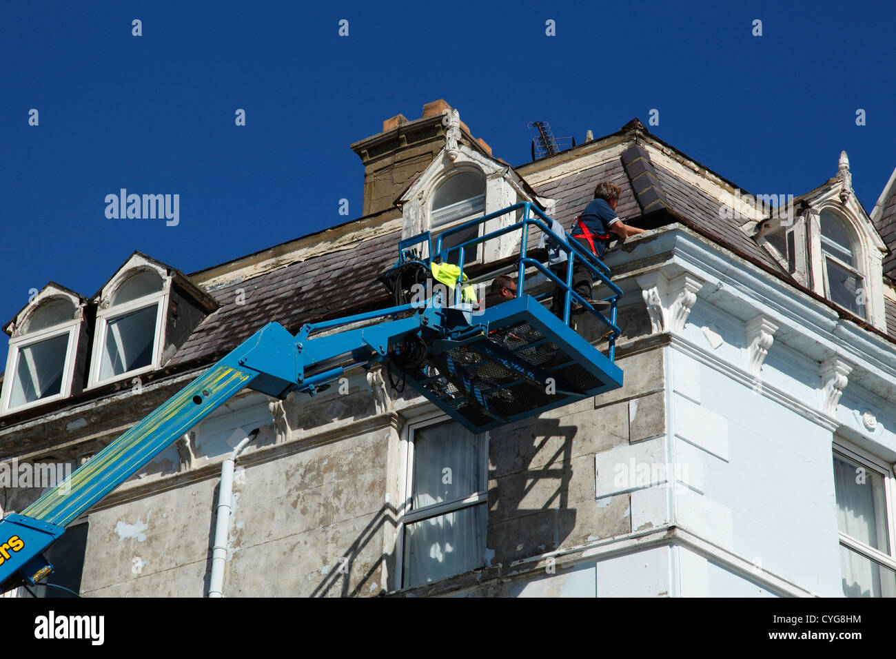 Arbeiter mit einer Hubarbeitsbühne, Dachrinnen auf Grundstück in Großbritannien zu reparieren Stockfoto