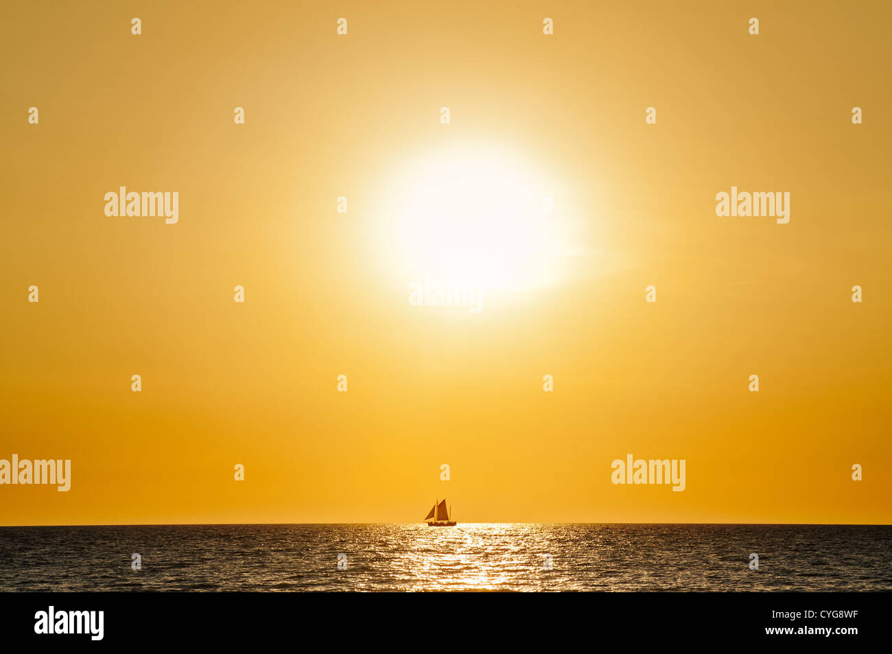 Segelboot vor der untergehenden Sonne am Horizont. Stockfoto