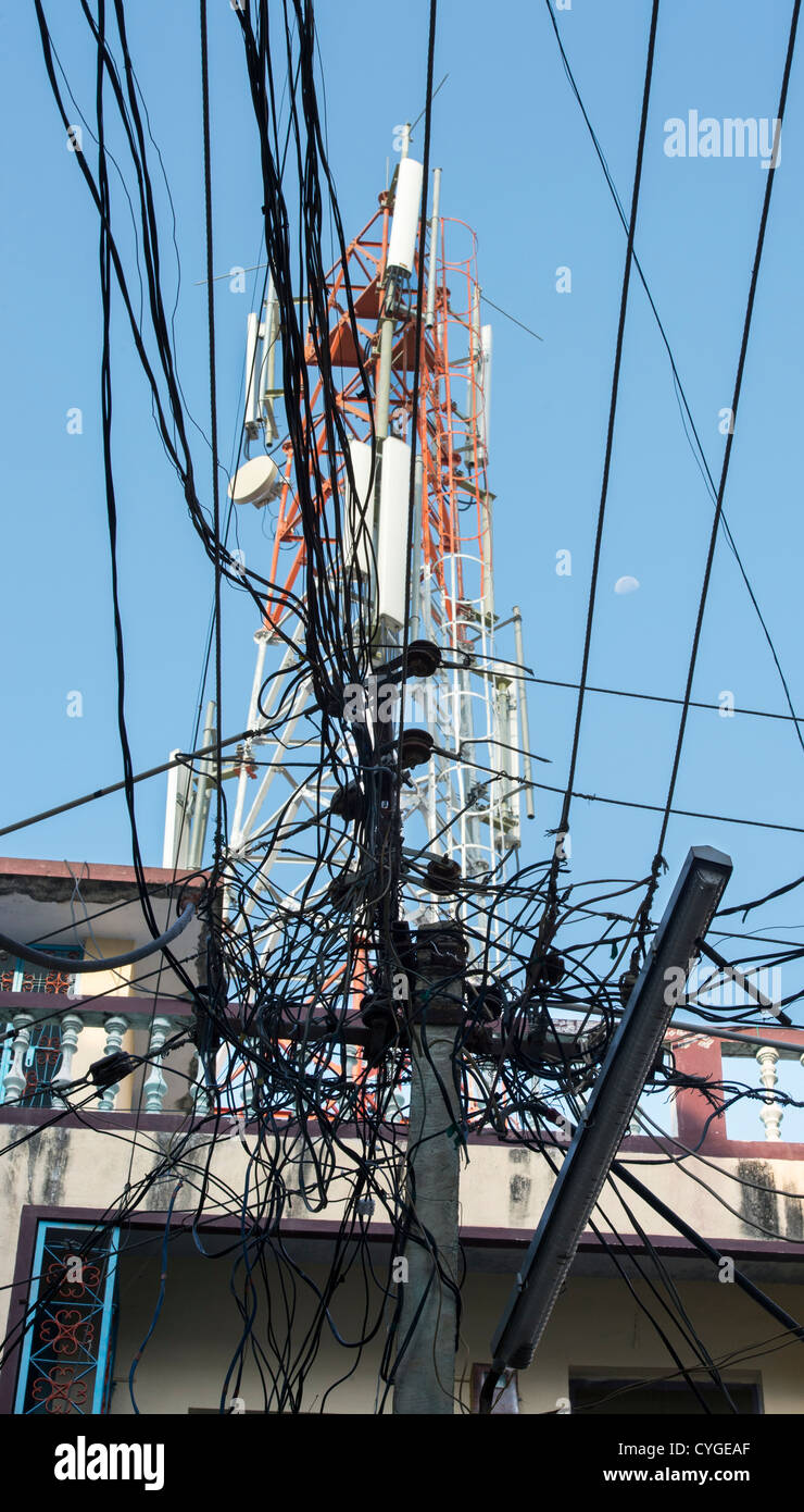 Strommasten und Kabel vor einem Telekommunikationsunternehmen Turm in einer indischen Straße. Andhra Pradesh, Indien Stockfoto