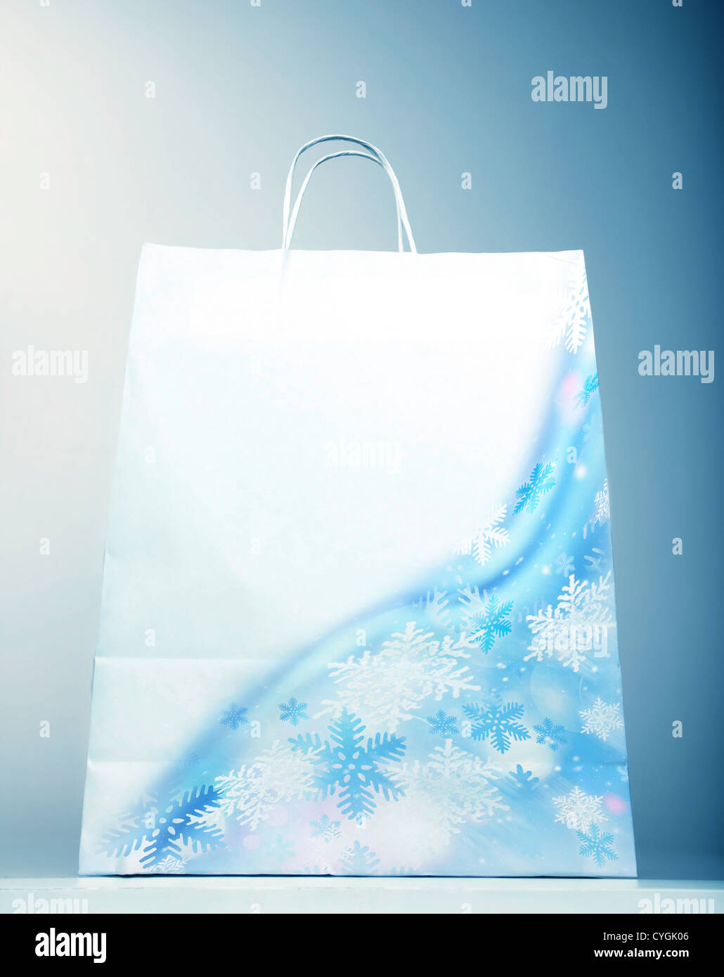 Bild von weißen Papiertüte mit schöne Schneeflocke isoliert auf blauem Hintergrund, Weihnachtsverkauf, Weihnachtszeit einkaufen Stockfoto