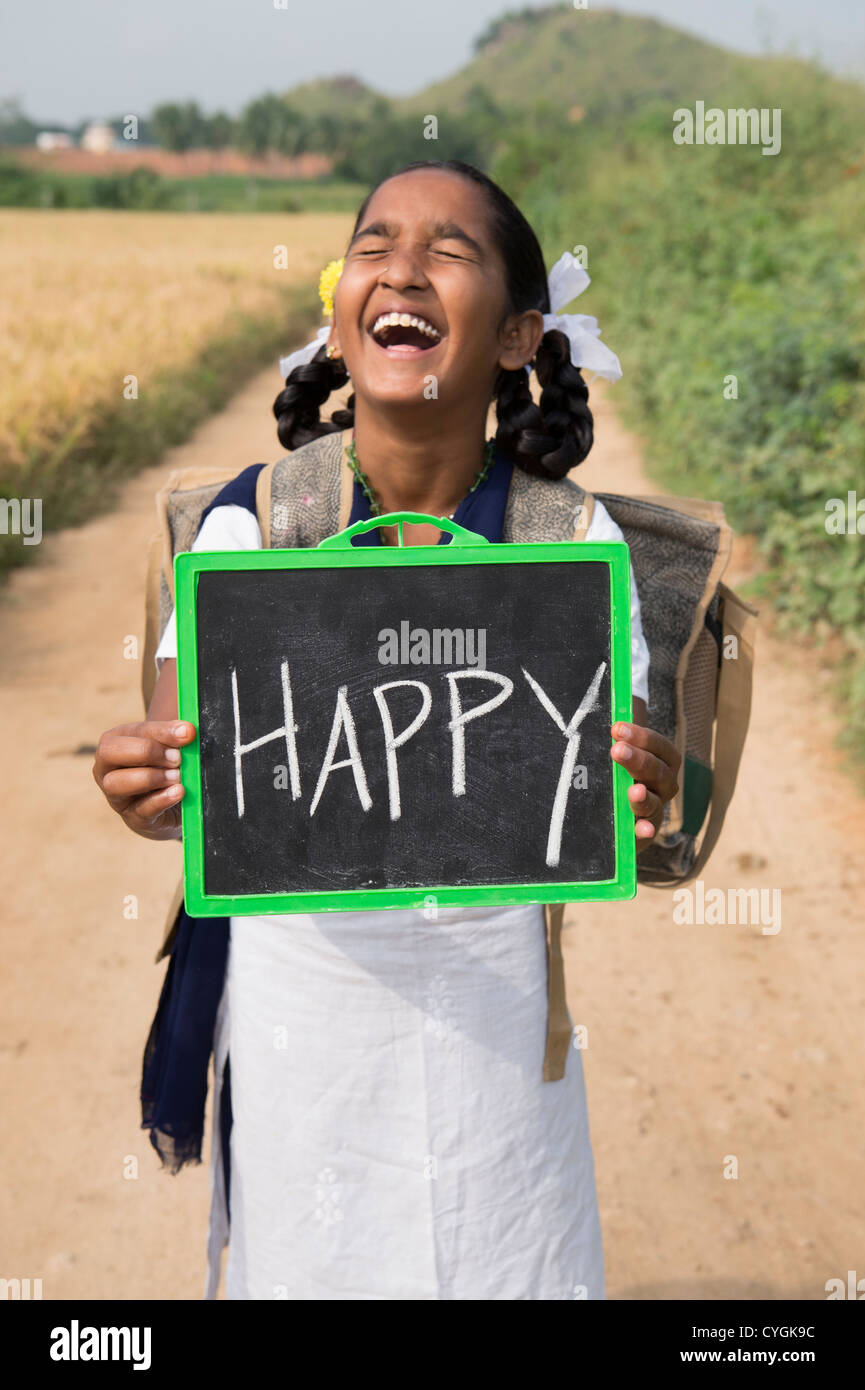 Lachende indische Schulmädchen mit einer Tafel mit fröhlichen darauf geschrieben. Andhra Pradesh, Indien Stockfoto