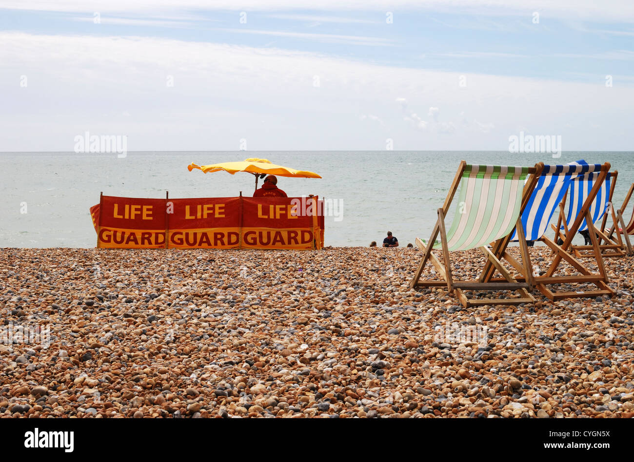 Rettungsschwimmer im Dienst am Brighton Beach mit Menschen sitzen in Liegestühlen. East Sussex. England Stockfoto