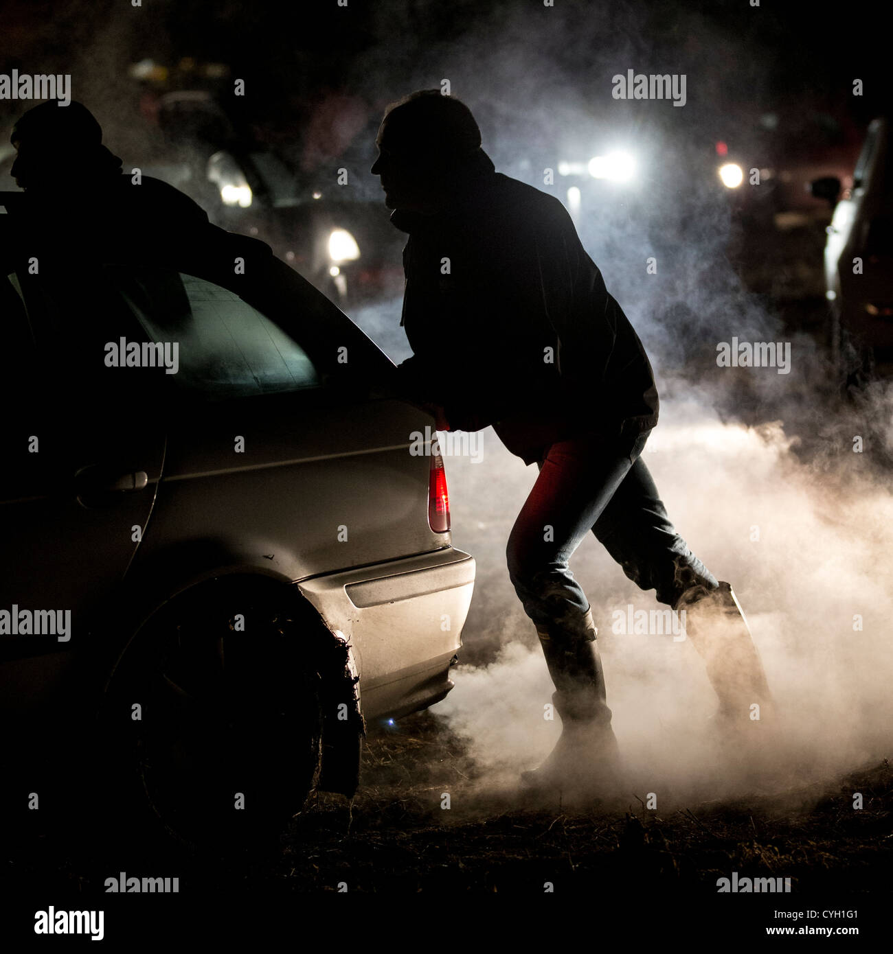 Autos stecken in einem schlammigen Feld in einer kalten Nacht nach einem Feuerwerk Stockfoto