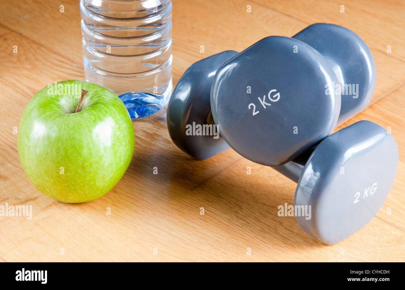 Paar Hanteln, grüner Apfel, Klebeband und eine Flasche Wasser zu messen. Bewegung und gesunde Ernährung Konzept. Stockfoto