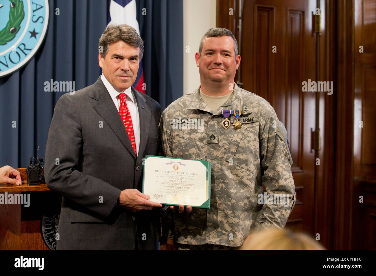 Texas-Gouverneur Rick Perry (l) präsentiert das Purple Heart und zwei weiteren Auszeichnungen Armee Flug Medic Stabsunteroffizier Patrick Rogers Stockfoto