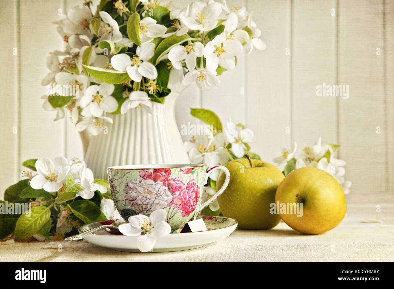 Teetasse mit frischen Blüten und grünen Äpfeln Stockfoto