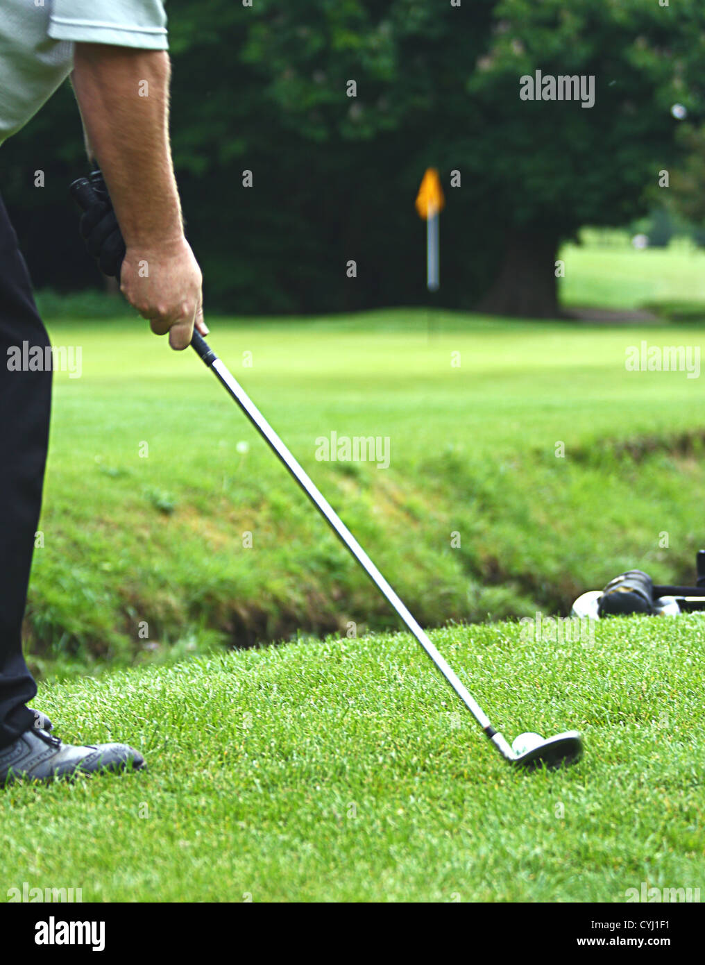 Chippen einen Golfball auf das Grün über einen kleinen Bach Stockfoto