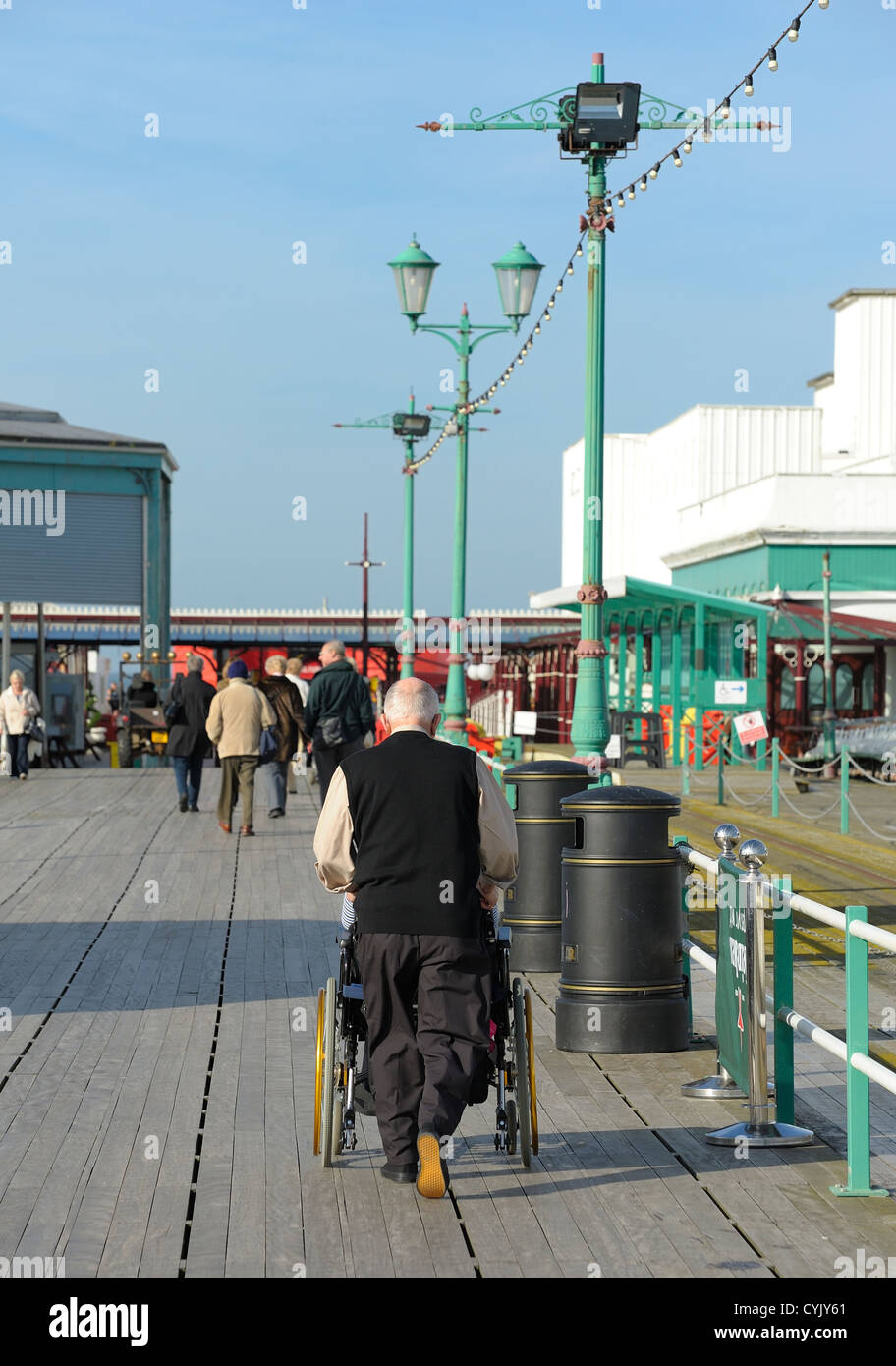 Ein Mann schieben einen Rollstuhl nach unten Central Pier Blackpool Lancashire England uk Stockfoto