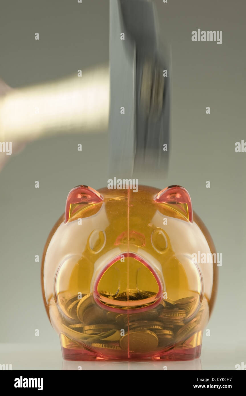 Orange transluzent Sparschwein mit sichtbaren Münzen innen und hammer Stockfoto