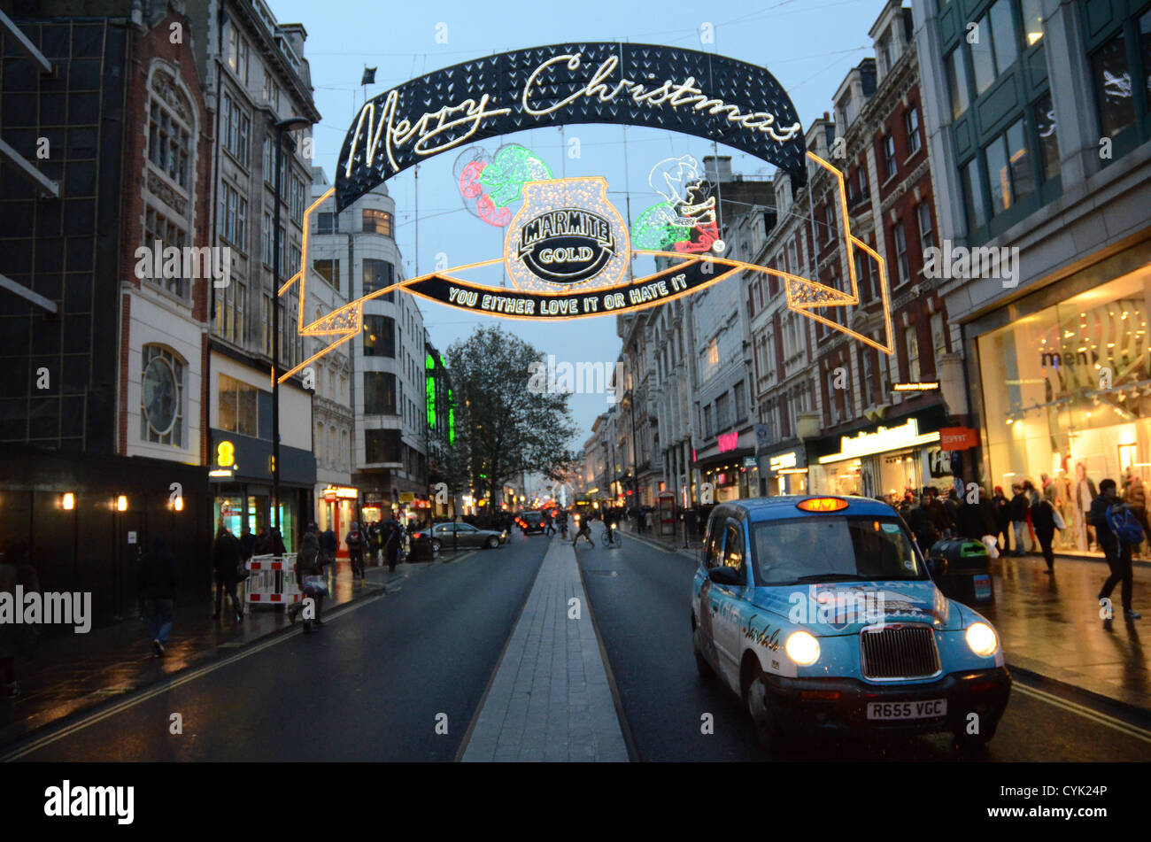 6. November 2012: Oxford Street Christmas Lights Sponsored by "Marmite Gold" Display zeigt ein Zeichen Tauchen in den Topf mit Marmite, während ein anderes Zeichen in eine Weihnachtsmütze in Bezug auf Marmite des lang andauernden Slogan "Sie entweder lieben oder hassen es" London, UK erbricht Stockfoto