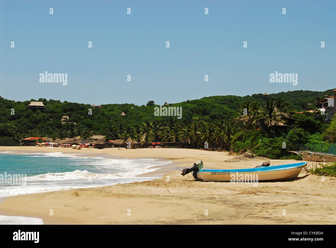 Mexiko, Mazunte, Blick auf ein Schiff vor Anker am Strand mit Bäumen, grünen Bergen und strohgedeckte Hütte im Hintergrund Stockfoto