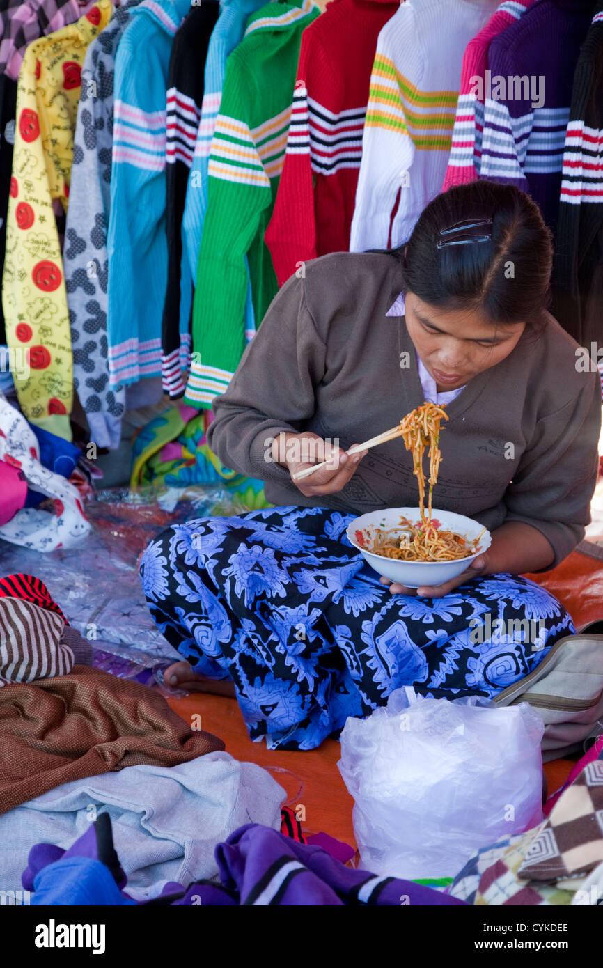 Myanmar, Burma. Kleidung-Lieferanten essen Nudeln mit Stäbchen, "Five-Day"-Markt, Inle-See, Shan-Staat. Stockfoto