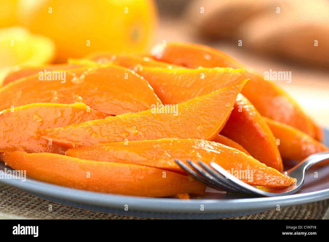 Sweet Potato Wedges karamellisiert mit braunem Zucker und frisch gepressten Orangensaft mit einer Gabel auf Platte, Orangen und Süßkartoffeln in der Stockfoto