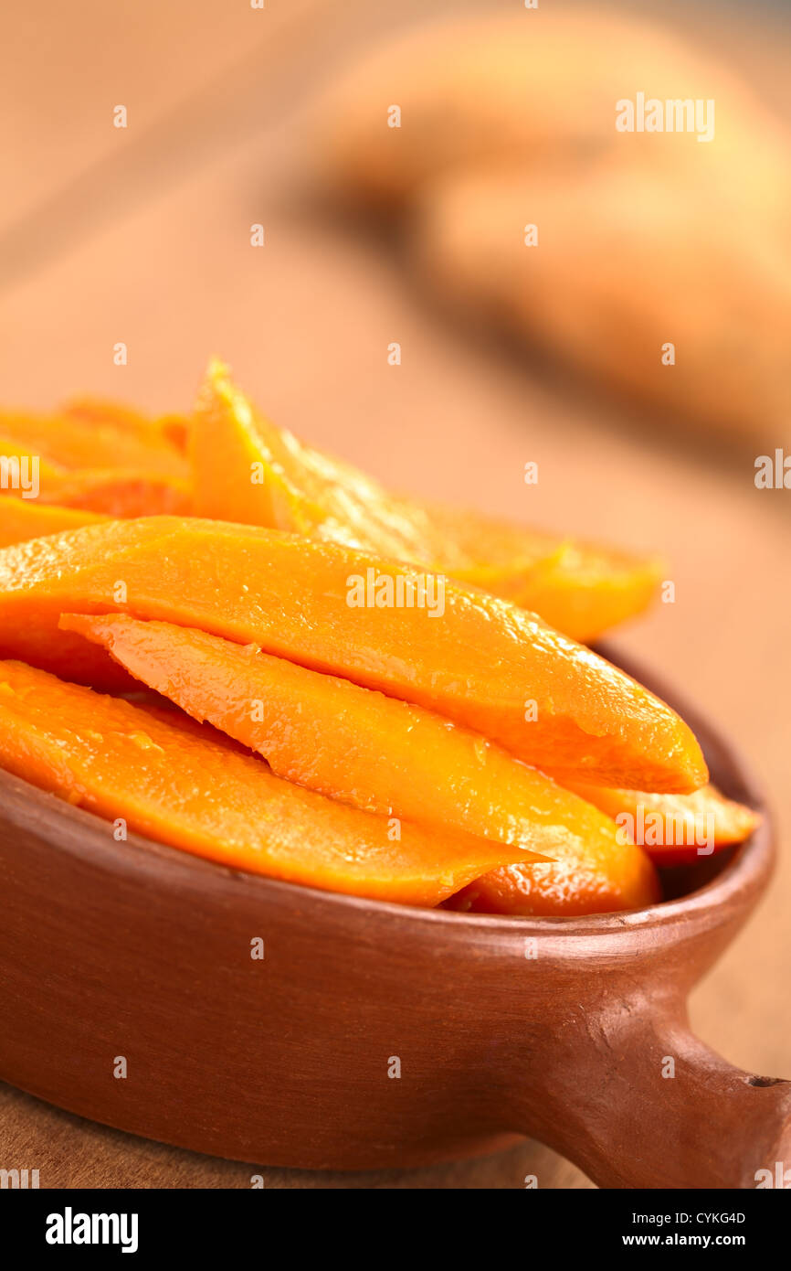 Sweet Potato Wedges karamellisiert mit braunem Zucker und frisch gepressten Orangensaft in rustikalen Schüssel mit Süßkartoffeln in den Rücken Stockfoto