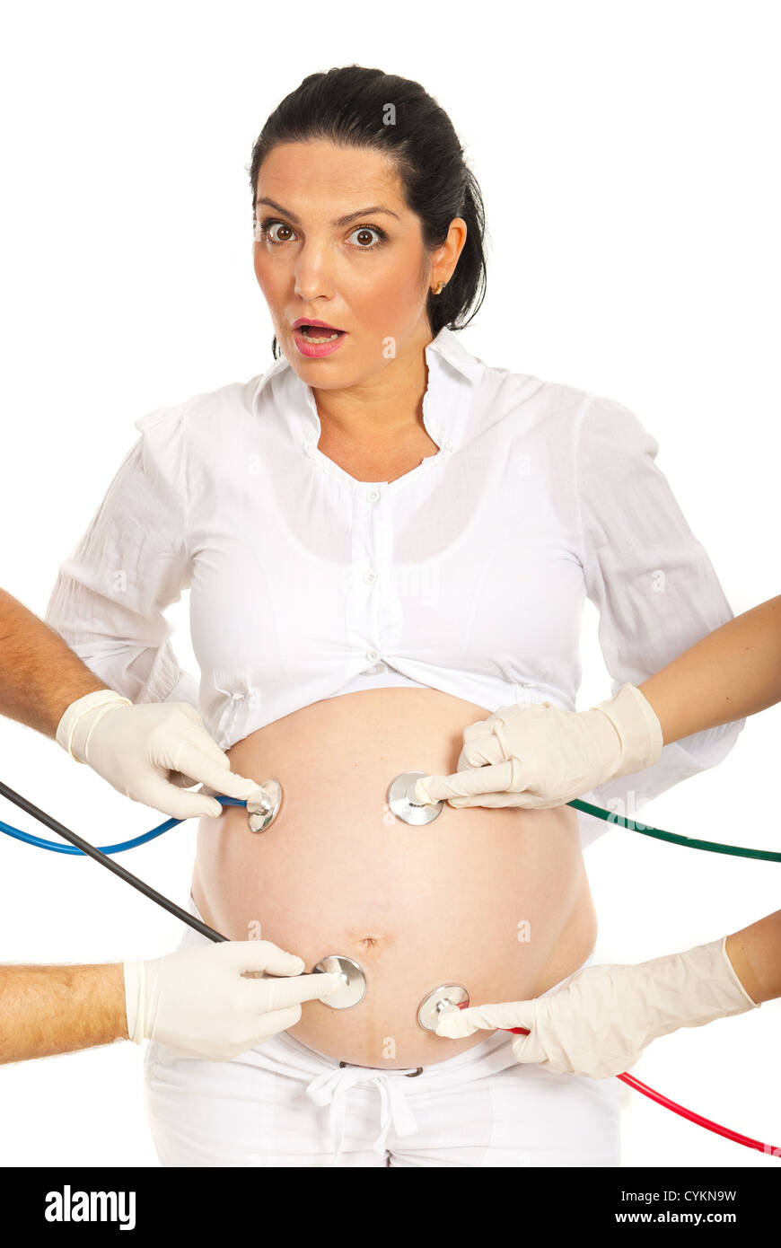Erstaunt schwangere Frau mit vielen Stethoskope untersuchen ihren Bauch isoliert auf weißem Hintergrund Stockfoto
