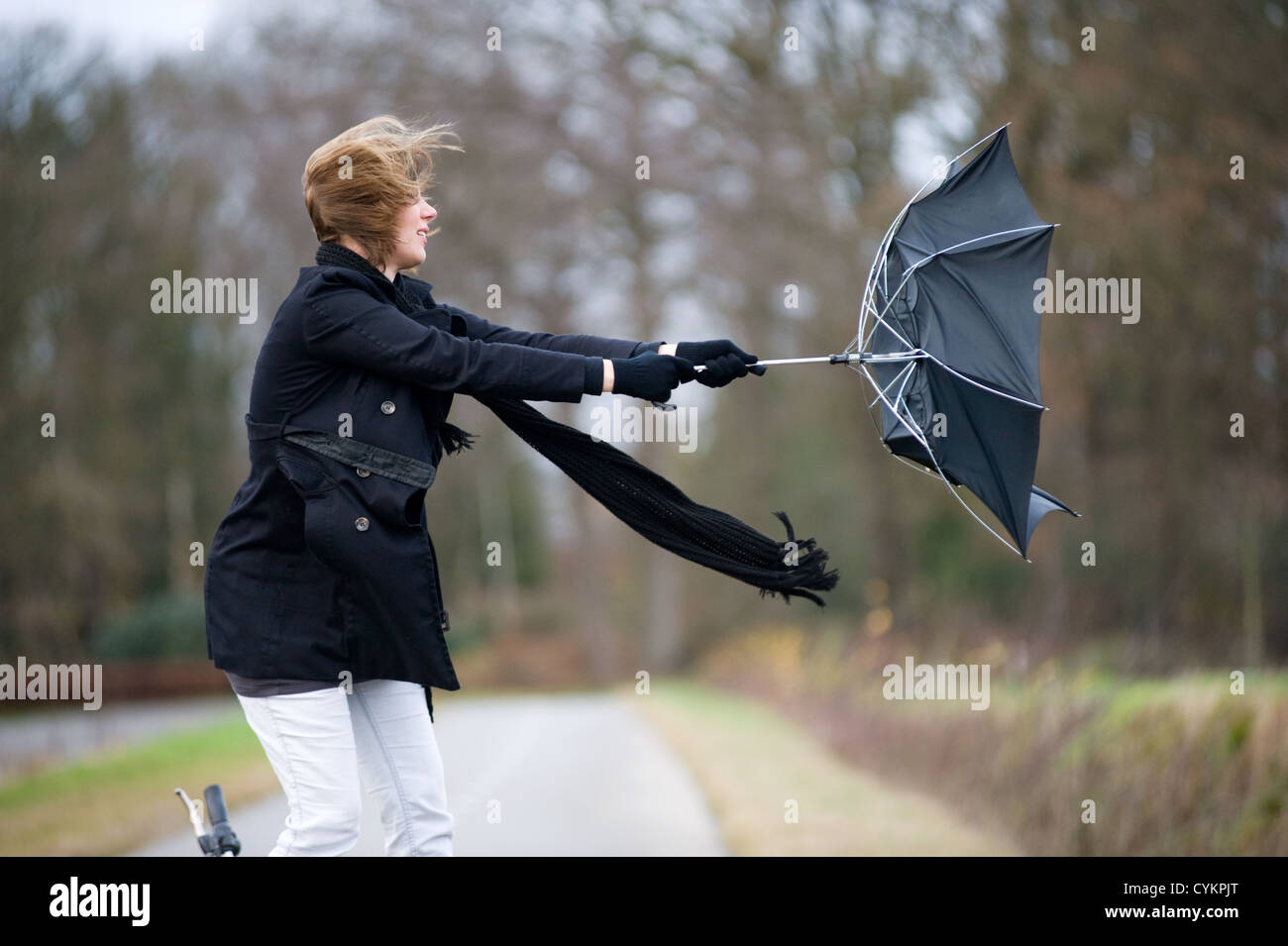Eine junge Frau kämpft gegen den Sturm mit ihrem Schirm Stockfoto