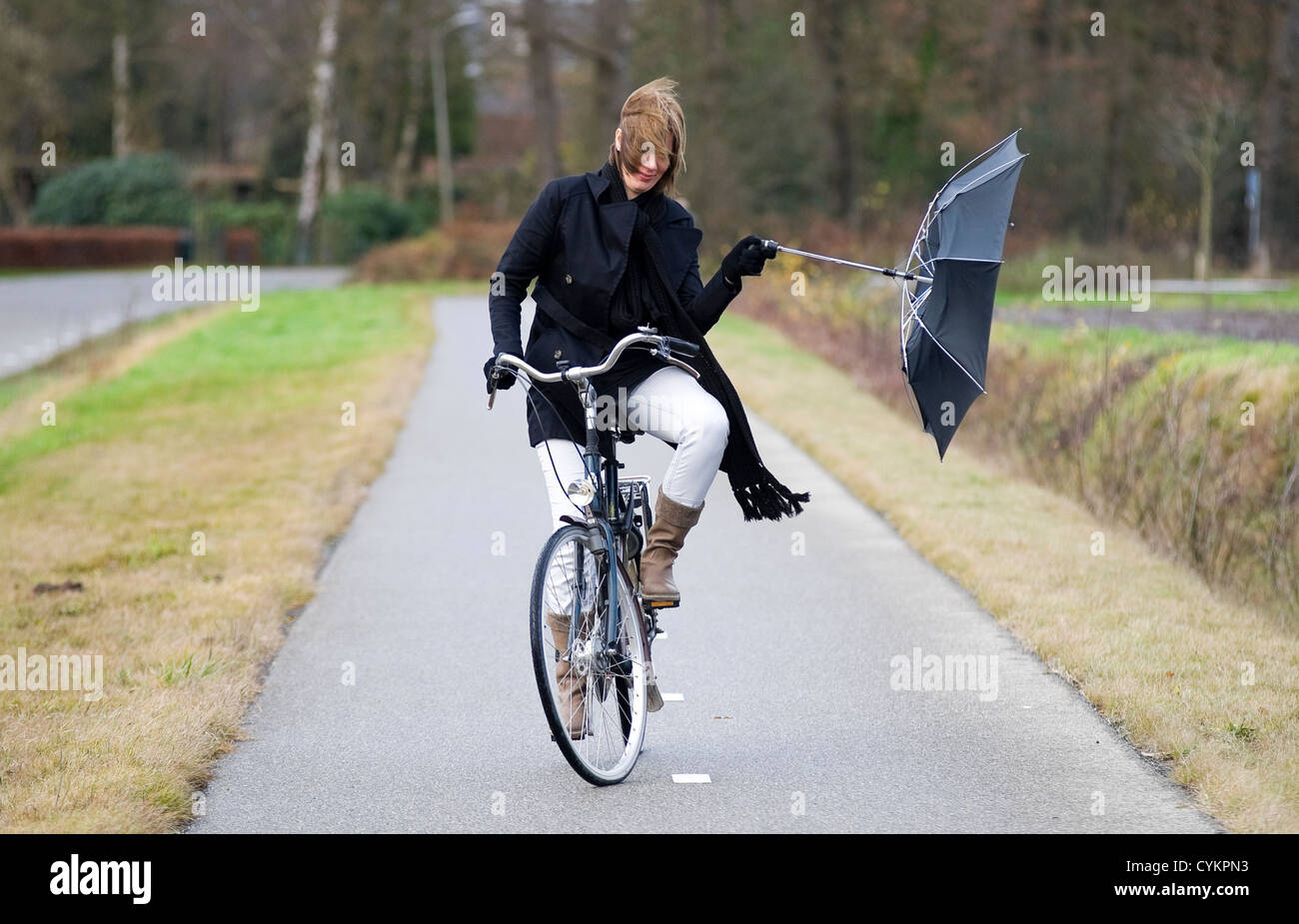 Eine junge Frau kämpft gegen den Sturm mit ihrem Schirm Stockfoto