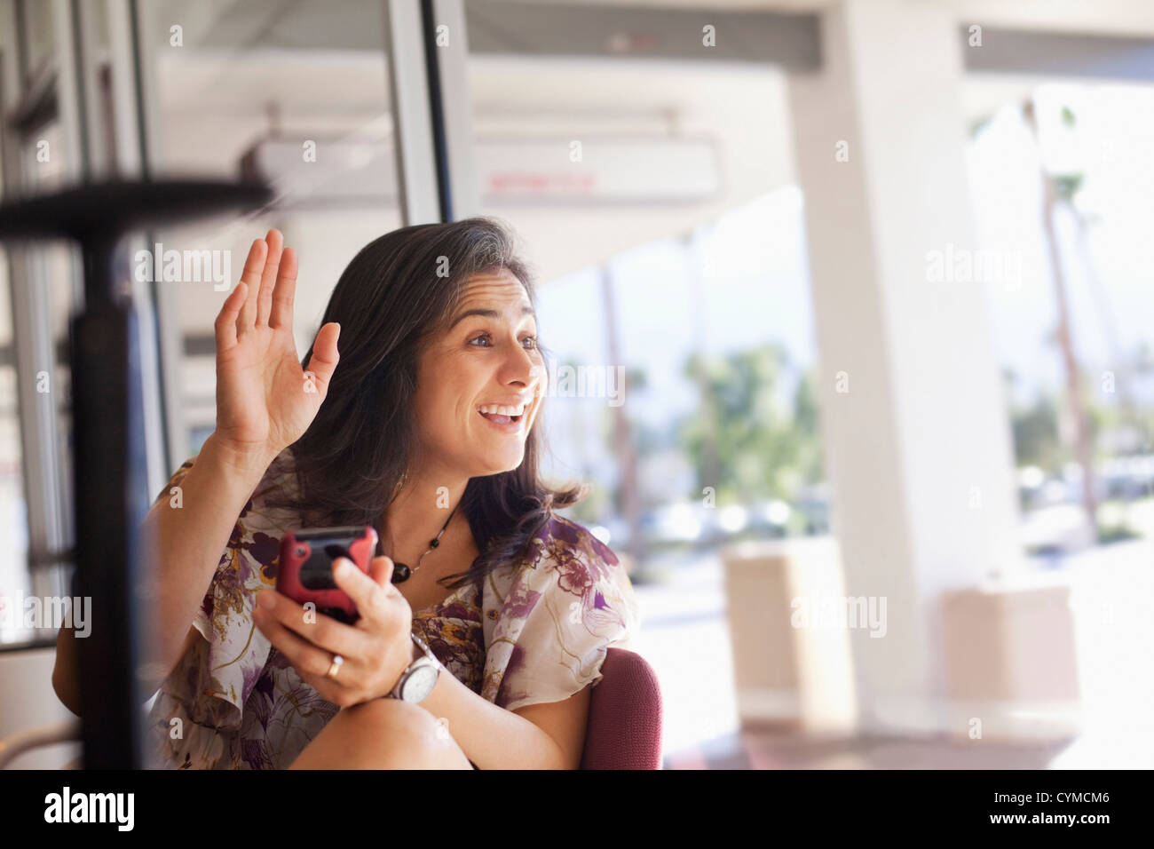 Hispanic Frau winken und halten Handy Stockfoto
