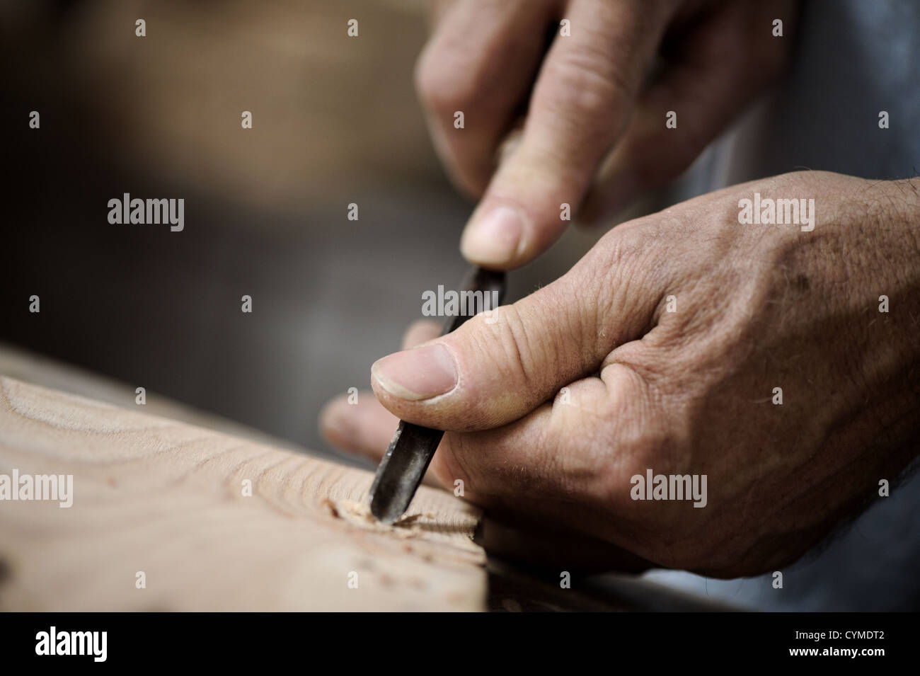 Hände des Handwerkers schnitzen ein Basrelief mit einem Beitel Stockfoto