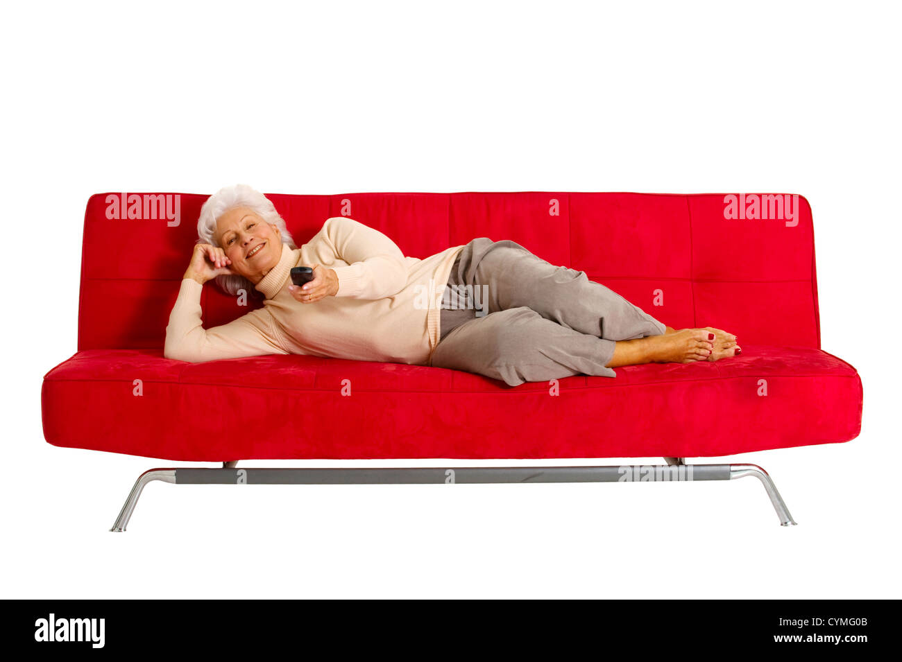 ältere Frau auf dem Sofa mit TV-Fernbedienung Stockfoto