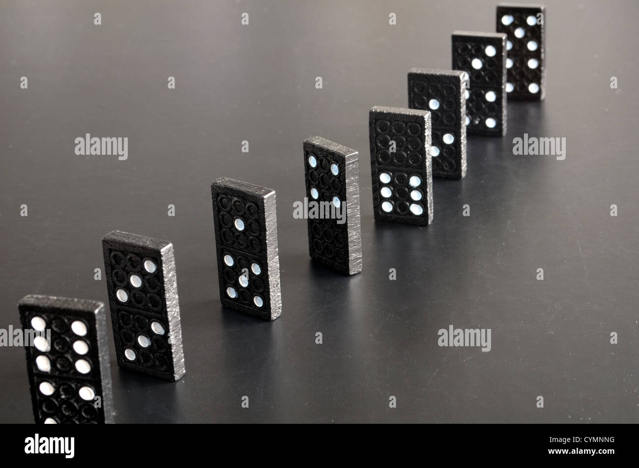 Finanzkrise-Konzept mit Domino-Spiel auf schwarzem Hintergrund Stockfoto