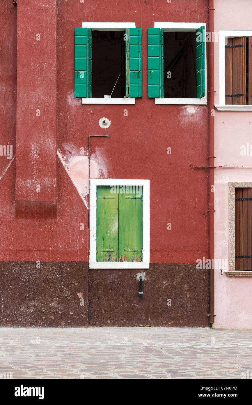 Eine rötlich-braune gemaltes Haus in Burano, Venedig, mit kontrastierenden grünen Fensterläden an den Fenstern Stockfoto
