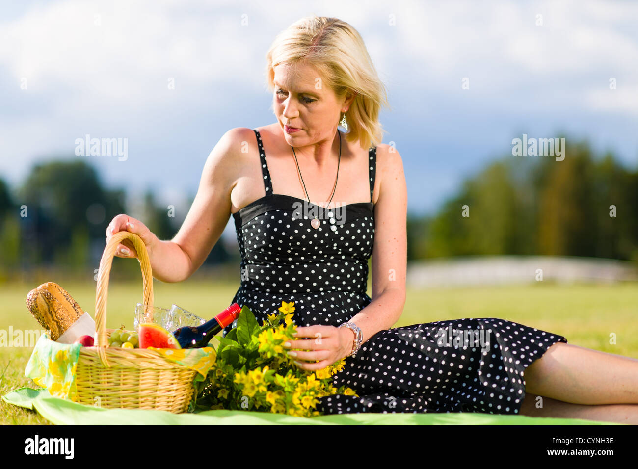 Allein Frau mit einem Picknick-Korb auf der Decke sitzen Stockfoto
