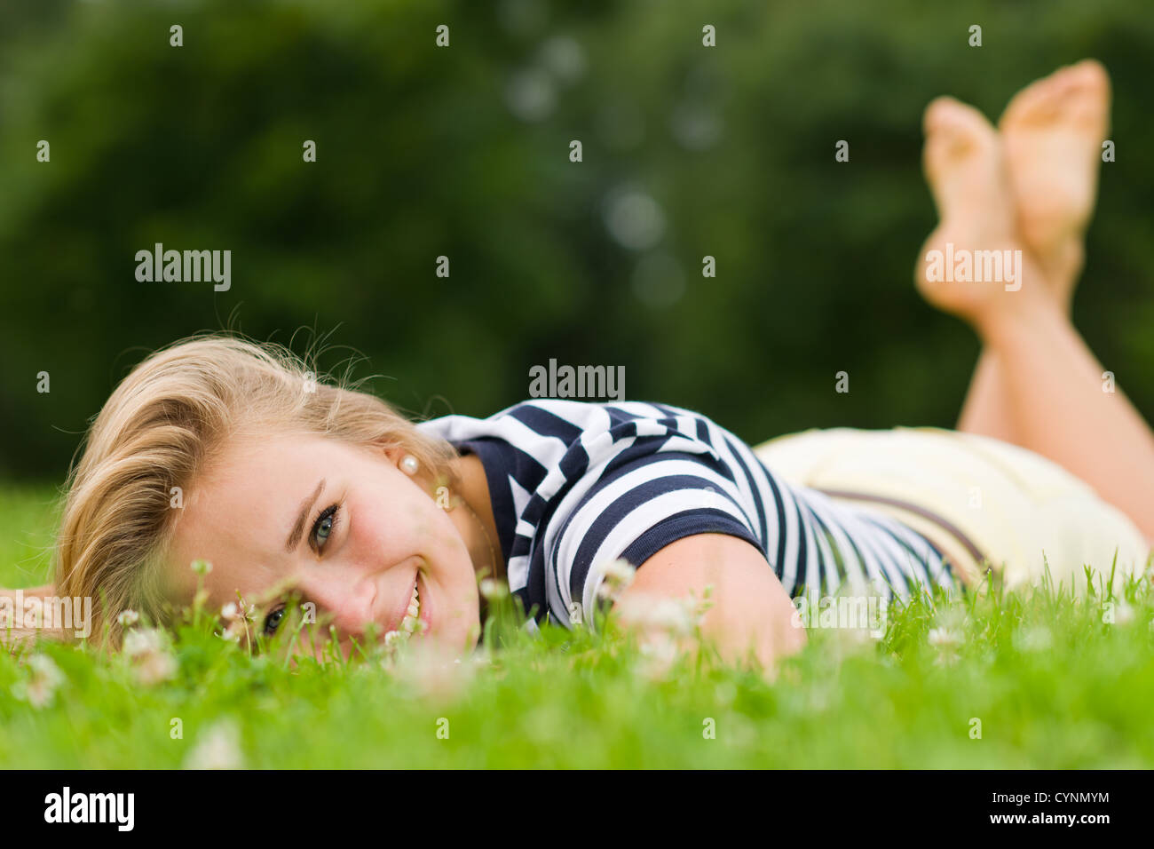 Lächelnde Mädchen auf dem Rasen liegend mit sehr engen Schärfentiefe und Fokus auf die Augen Stockfoto