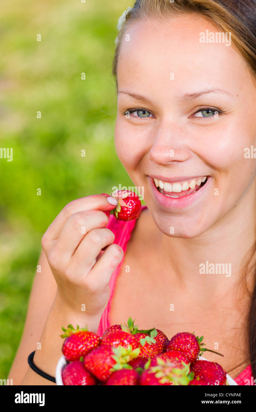 Schönes Mädchen eine Erdbeere, volle Schüssel mit Beeren schmecken, konzentrieren sich auf die Augen Stockfoto