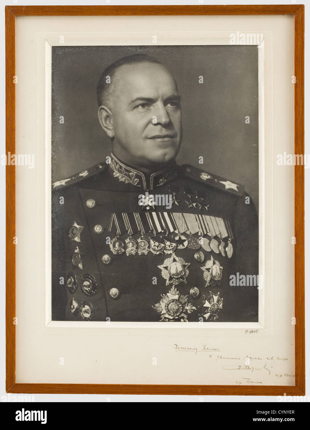 Marschall Georgy Konstantinovich Zhukov (1896 - 1974) - ein Foto mit Widmung an General Koenig, Portraitbild in Marschalluniform mit zahlreichen Medaillen. Die Halterung mit einer kyrillischen Widmung handschriftlich in dunkler Tinte "An den französischen General Koenig, respektvoll Marschall Zhukov, Stadt Berlin 11/09/45". Rechts unten die Handschrift des Fotografen G. Schleier'. Gerahmt und unter Glas, Abmessungen 55 x 42 cm. Marschall Zhukov war Chef des Generalstabs und Sowjetrepublik für Verteidigung. Er wurde dafür bekannt, dass er Moskau erfolgreich verteidigt und siegreich in Th. Stockfoto