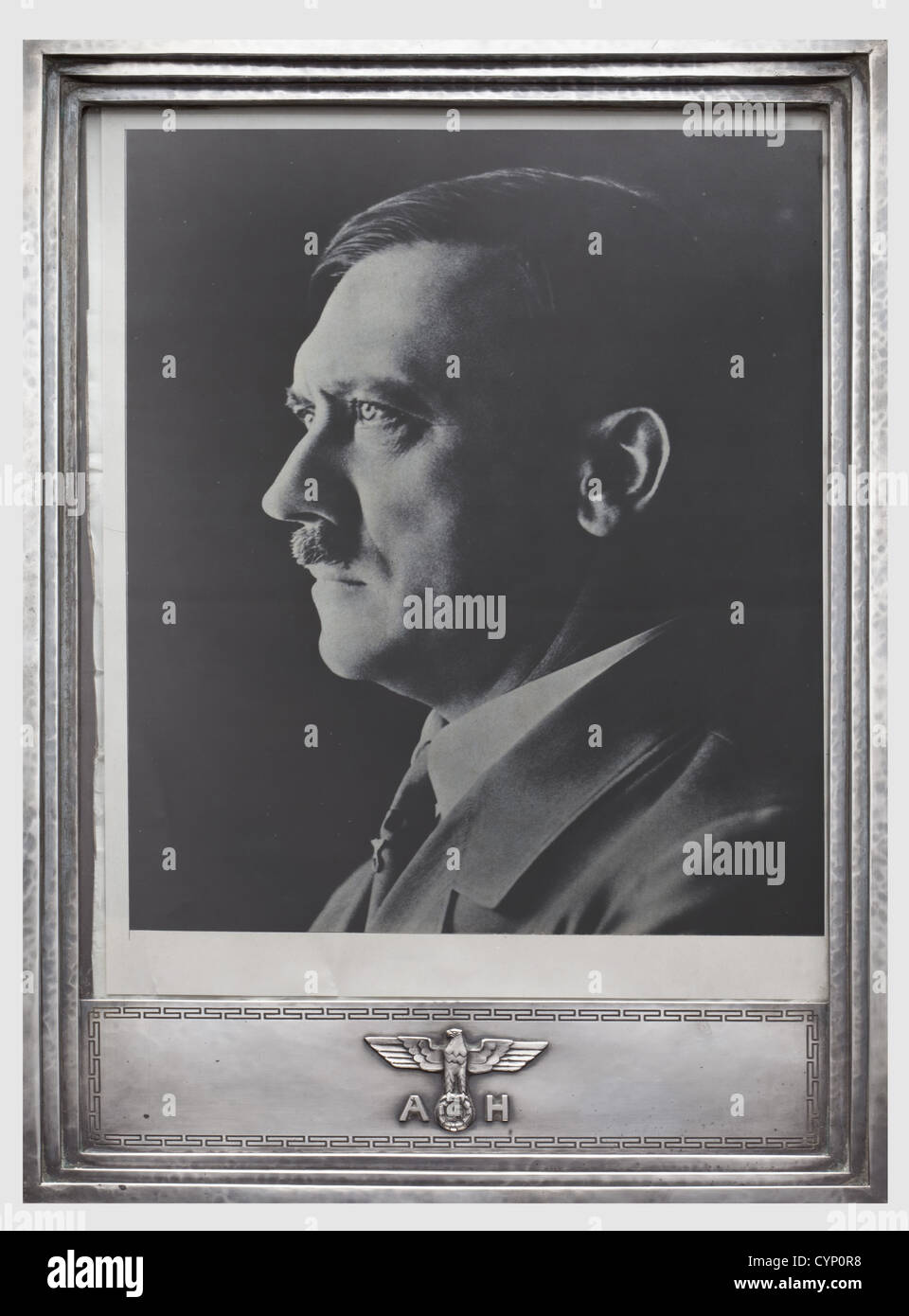 Adolf Hitler - ein offizieller silberner Präsentationsrahmen, Handgehämmter silberner Rahmen mit dreifach gestuftem Profilrand und nationalem Adler-Emblem, der an der unteren Grenze mit den Initialen "A" und "H" angebracht ist und von einem Mäanderband umgeben ist. Obere Felge mit gestripptem Herstellerzeichen "FHW" für Hermann Wandinger, München, und Kennzeichen "925" sowie Halbmond und Krone. Mit weinrotem marokkanischem Leder, mit Halt. Inklusive Glas, dem Foto ein gedrucktes Porträt eines zeitgenössischen Magazins. 34,5 x 24 cm, Menschen, 1930er, 1930er, 20. Jahrhundert, NS, Nationalsozialismus, Na, Stockfoto